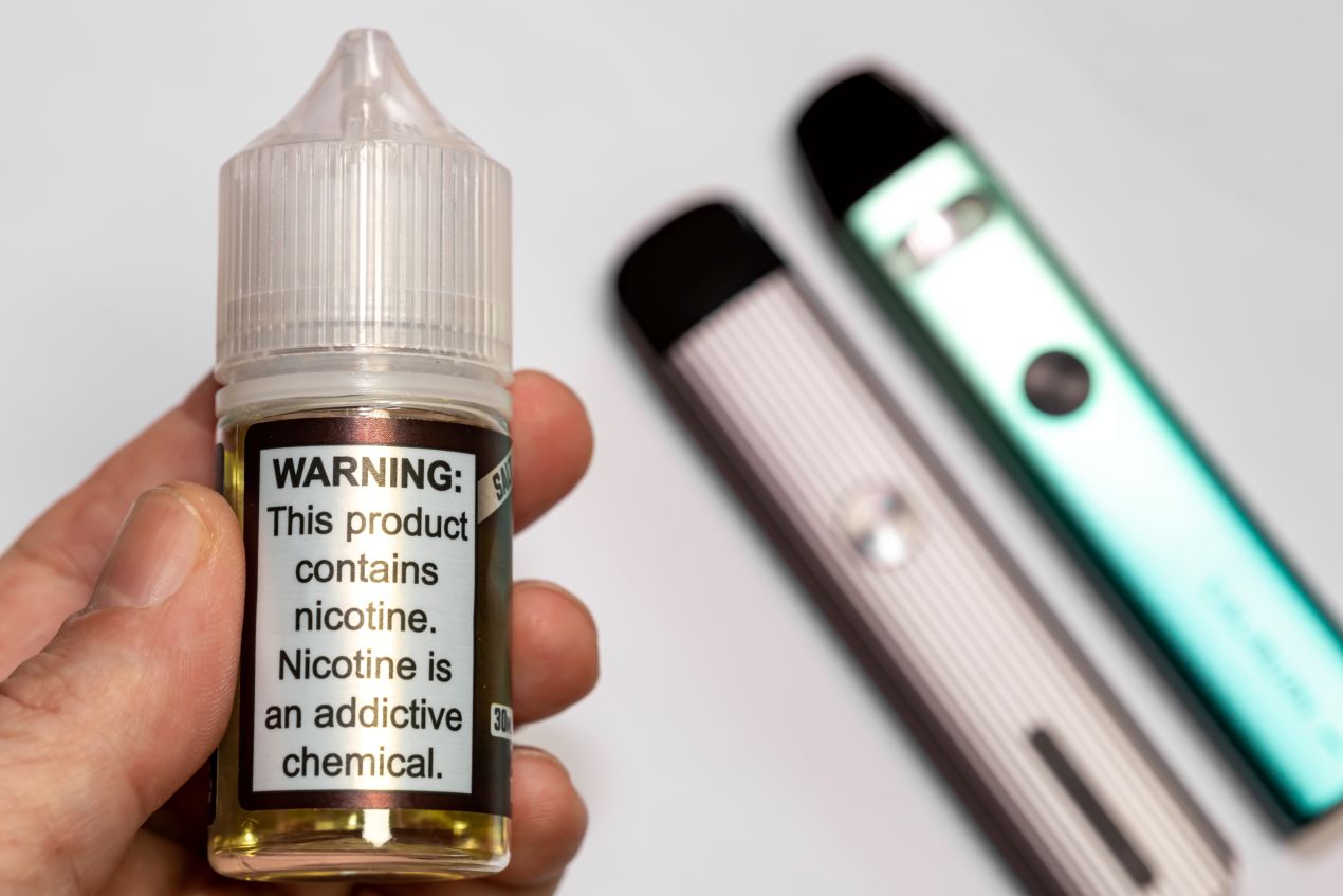 Flasche mit Nikotin­satz-Liquid und zwei Vape-Pods – neue Form des Nikotinkonsums im Detail
