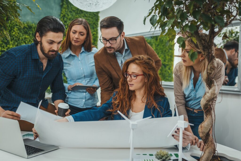 Team plant nachhaltige Projekte mit Windradmodell im Büro | umweltgerechte Straßenreparatur